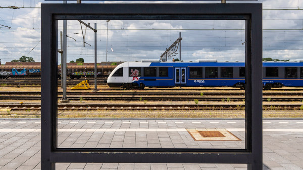 Een blauwwitte trein van Arriva staat gerangeerd op een verdergelegen spoor van station Venlo.