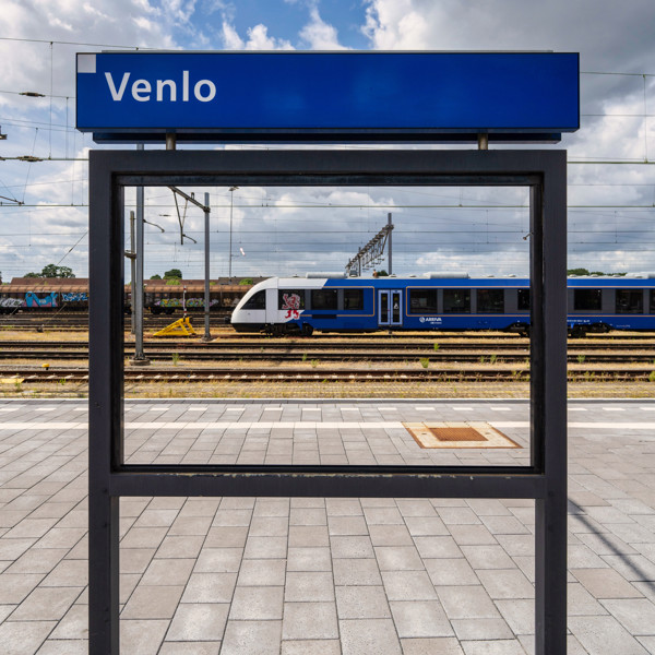 Een blauwwitte trein van Arriva staat gerangeerd op een verdergelegen spoor van station Venlo.