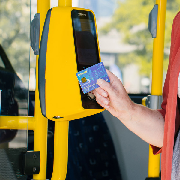 Iemand houdt een betaalpas voor een gele incheckpaal in een bus van Arriva.