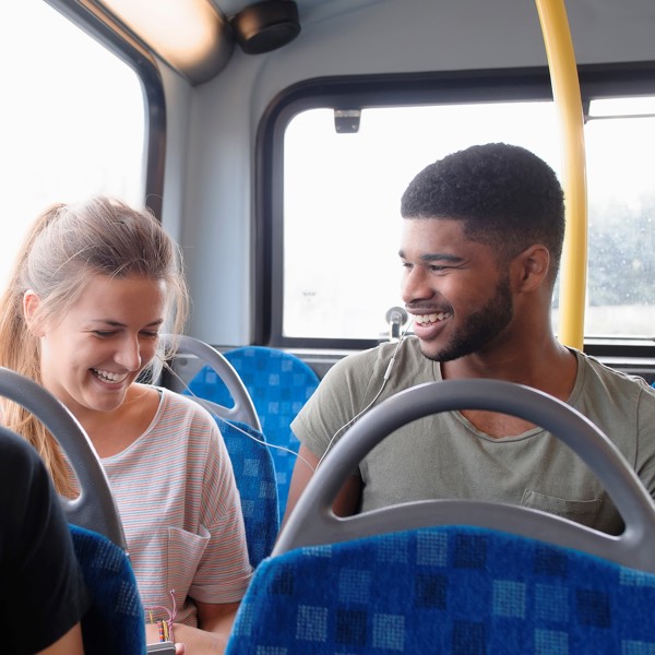 Een man en vrouw lachen samen terwijl ze naast elkaar in een bus van Arriva zitten.