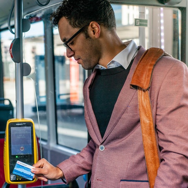 Mannelijke reiziger in kleurig pak en met schoudertas checkt in de bus in.